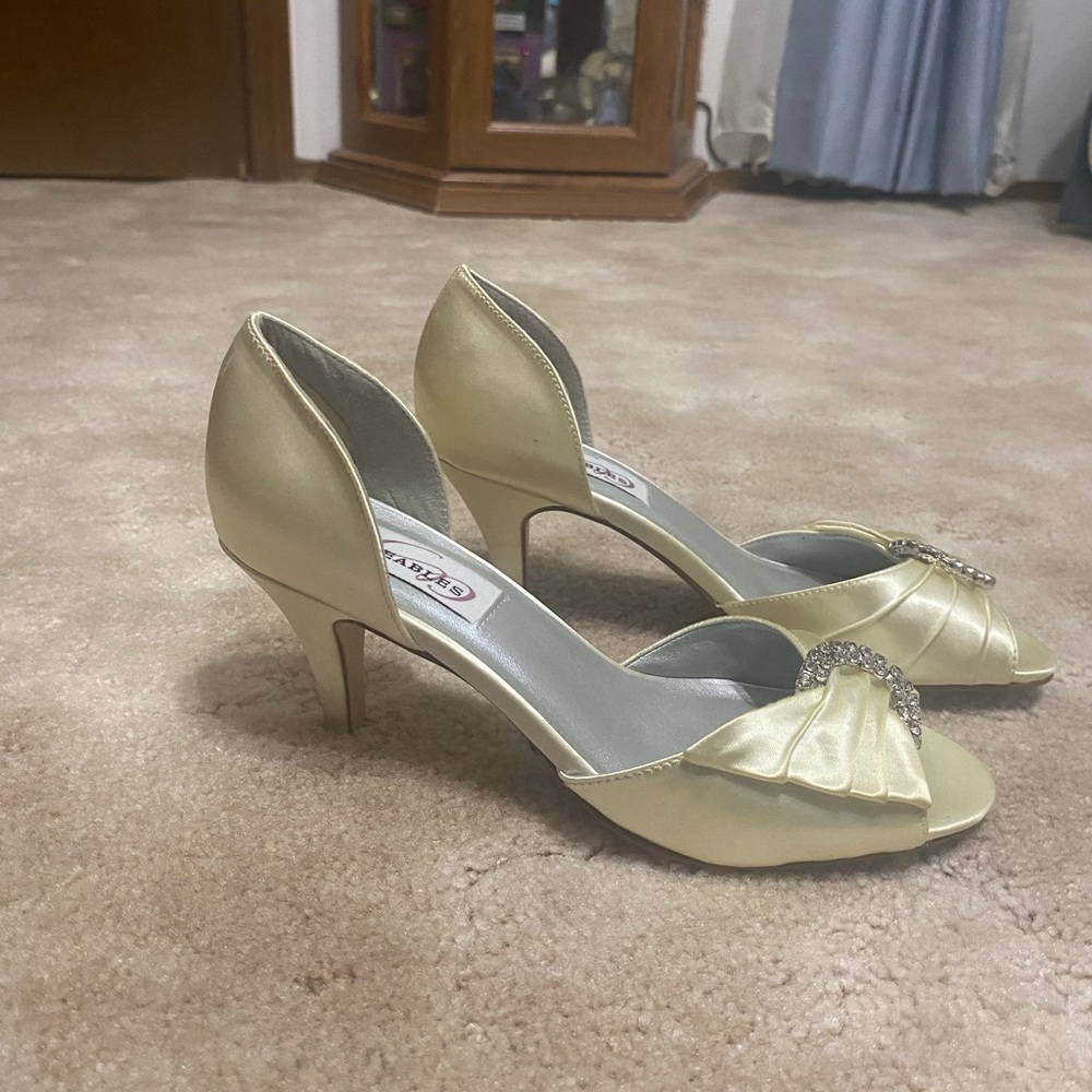 Cream colored satin high heels with rhinestone broach on top.  Size 6.5. 3” heel